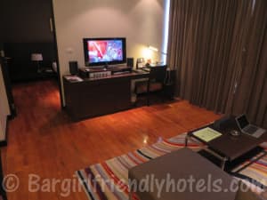 Living room with TV and sofa corner and bedroom in the back at Fraser Suites Sukhumvit Serviced Apartment