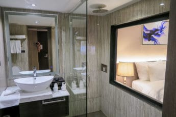 Bathroom has rainshower with see-through window at Arte Hotel in Bangkok